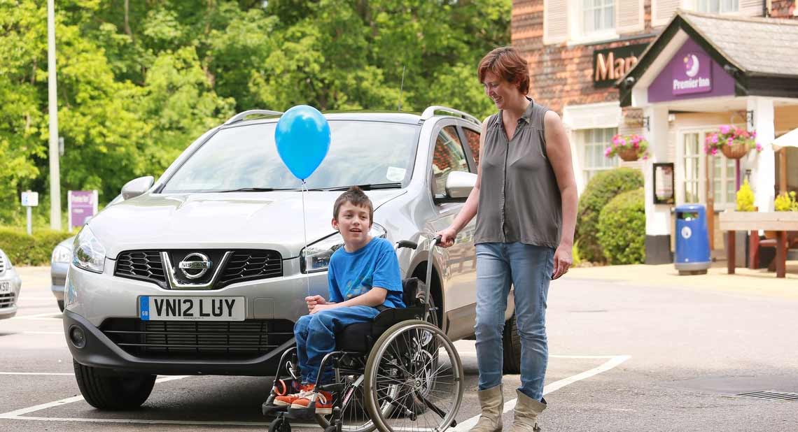 Happy mother and son with their mobility car